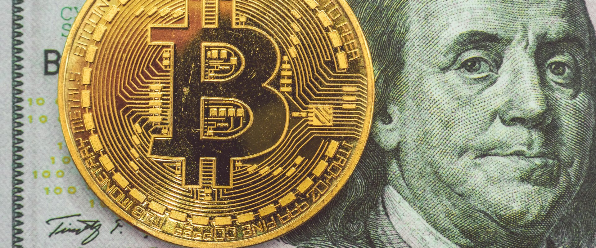 A bitcoin on top of a dollar bill